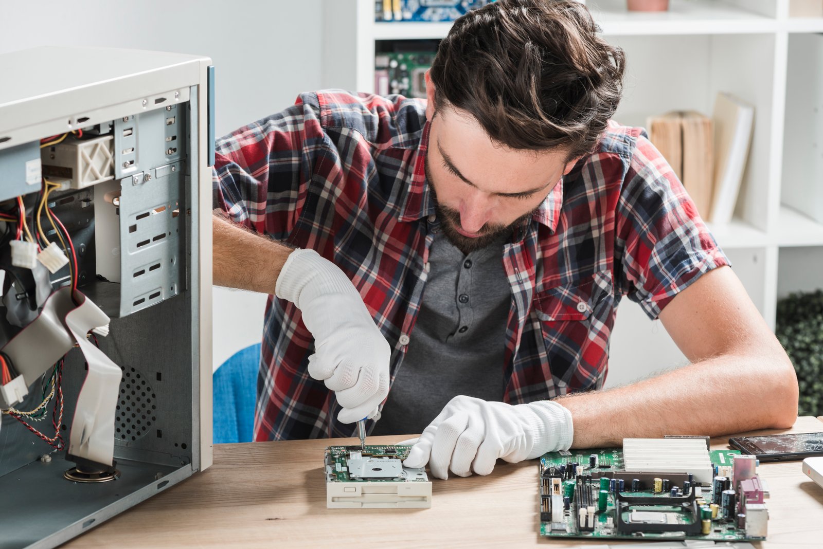 young-male-technician-wearing-gloves-fixing-computer-motherboard-with-screwdriver